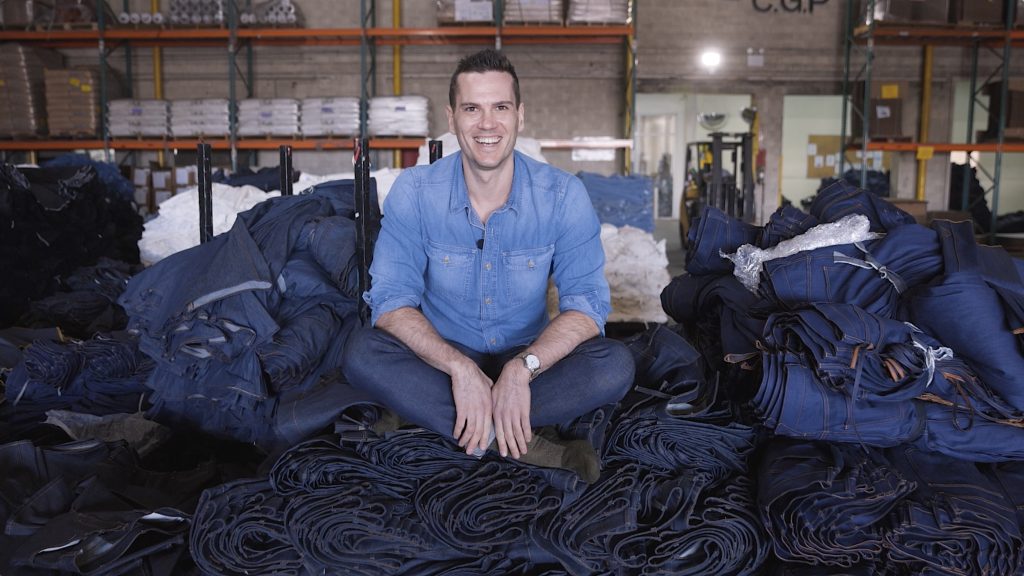 Nick sitting on a pile of jeans at the hiroshi kato factory